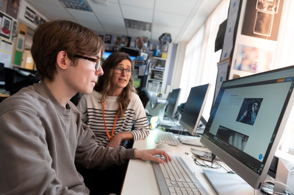 Student and Teacher working at cimputer at Abbey College Manchester